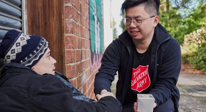 A Salvos worker offers a hand to man sheltering in a laneway.