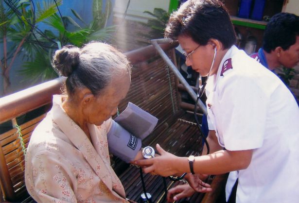 Indian Salvationist offering medical assistance to an elderly woman