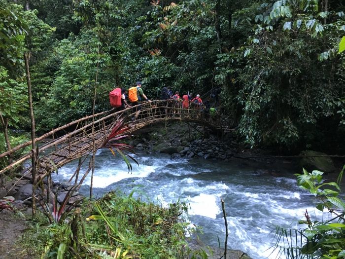 Trekkers crossing river on a bamboo bridge